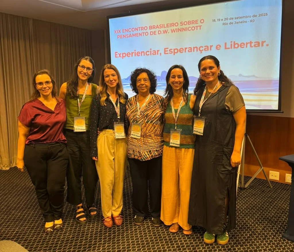 Integrantes da equipe Habitare reunidas diante de uma apresentação em um auditório.